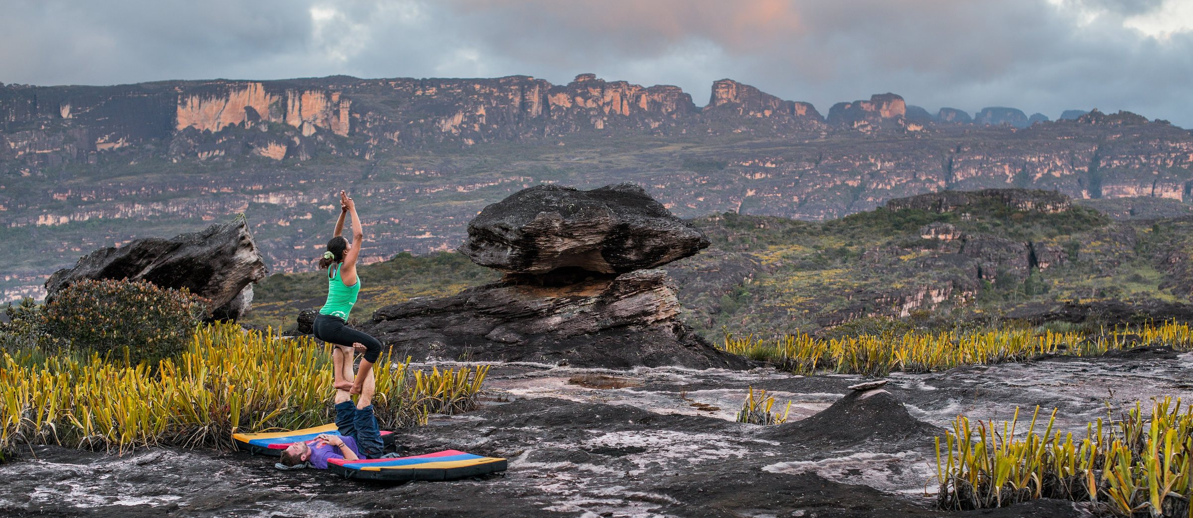 Acro yoga on the summit plateau of Auyán-tepui, the tepui ridge behind